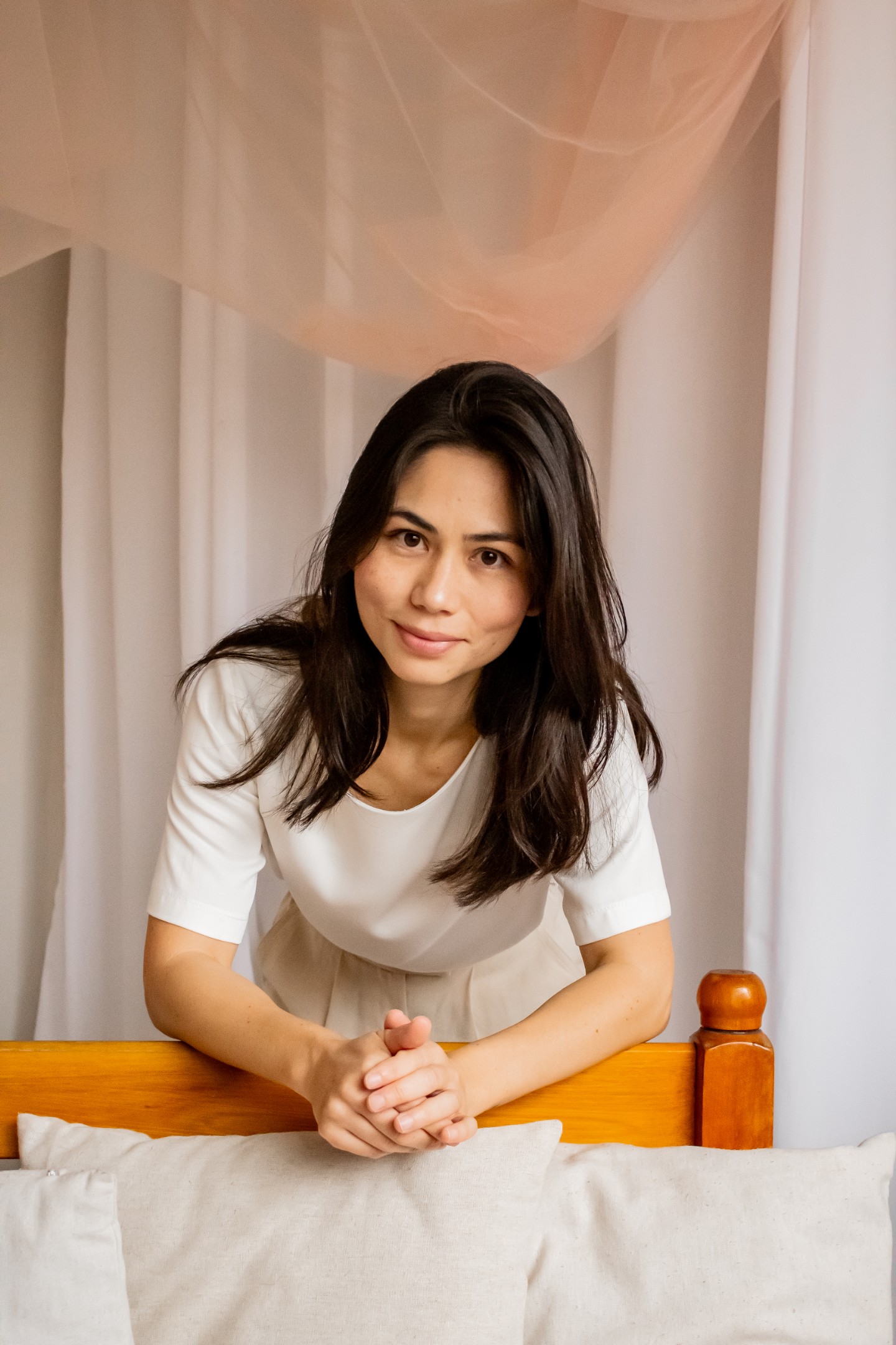Letícia Barone apoiada na cama, olhando para a câmera